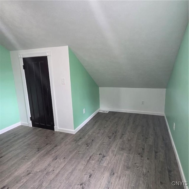 bonus room featuring vaulted ceiling, baseboards, and wood finished floors