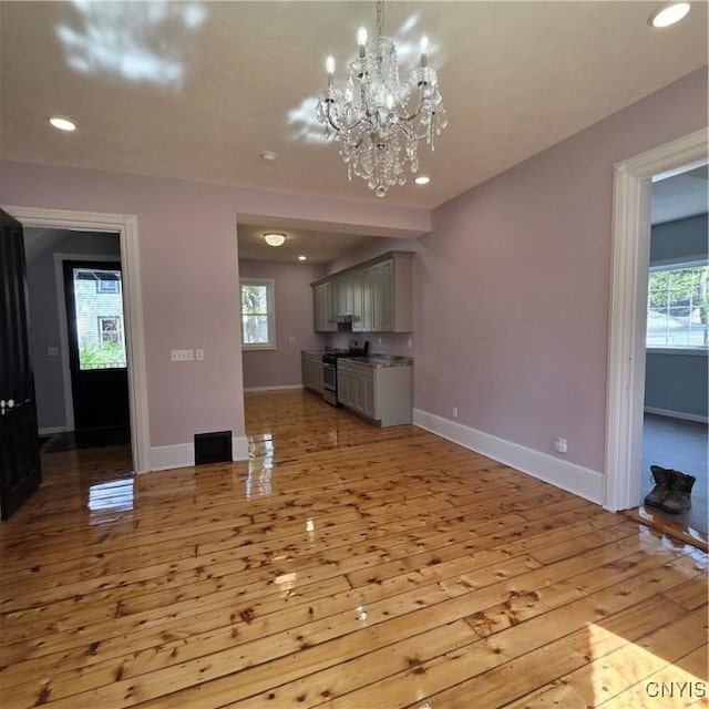 unfurnished living room featuring baseboards, light wood-style floors, a chandelier, and recessed lighting