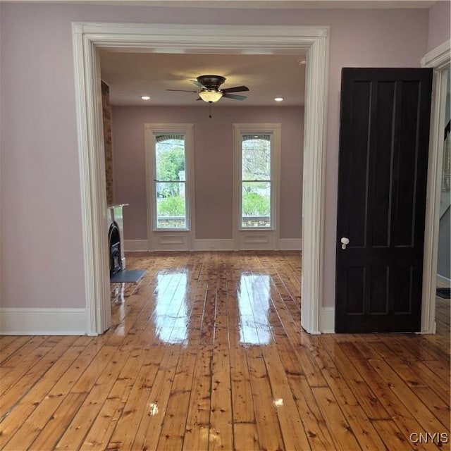 interior space with baseboards, a ceiling fan, and wood-type flooring