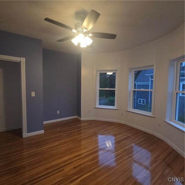 unfurnished room with ceiling fan, baseboards, and wood finished floors