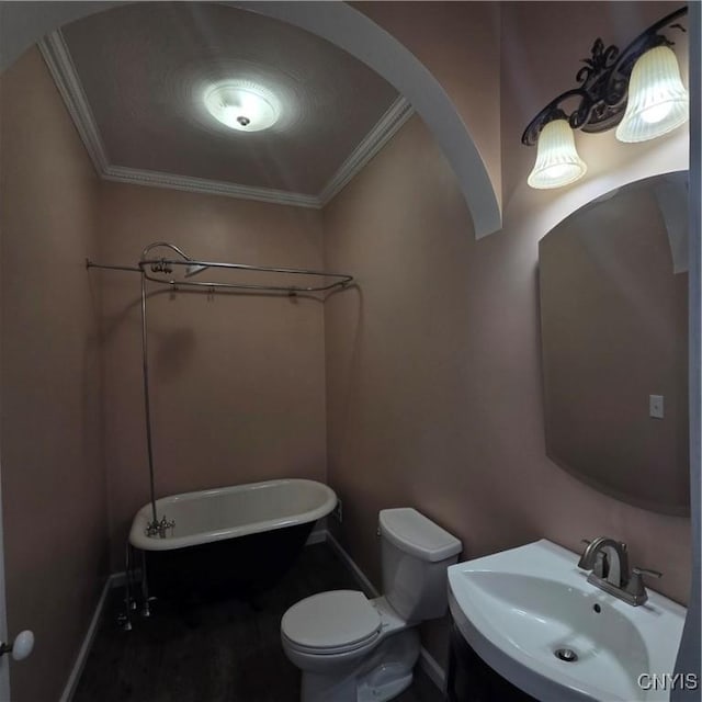 full bath featuring baseboards, toilet, ornamental molding, vanity, and a freestanding tub