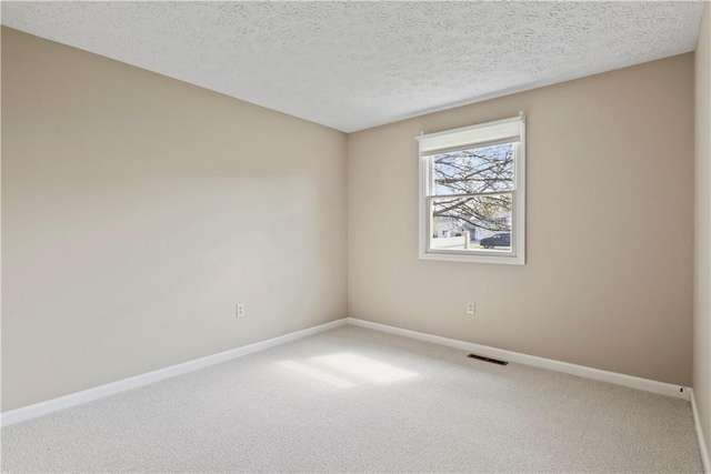 carpeted spare room featuring a textured ceiling, baseboards, and visible vents