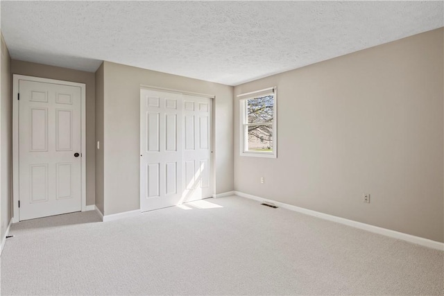 unfurnished bedroom featuring carpet, a textured ceiling, a closet, and baseboards