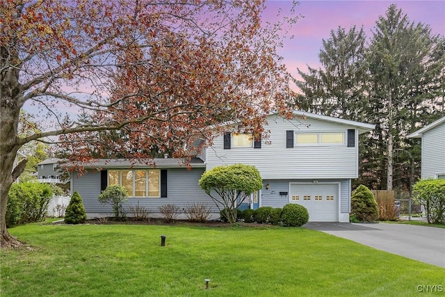 view of front facade with a yard, concrete driveway, a garage, and fence