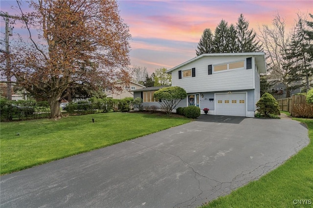 view of front of home with a lawn, fence, a garage, and driveway