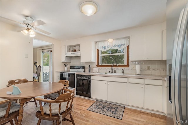 kitchen with a sink, range with electric stovetop, dishwasher, under cabinet range hood, and stainless steel fridge