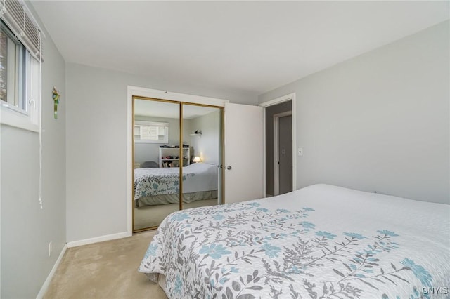 bedroom with a closet, light carpet, and baseboards