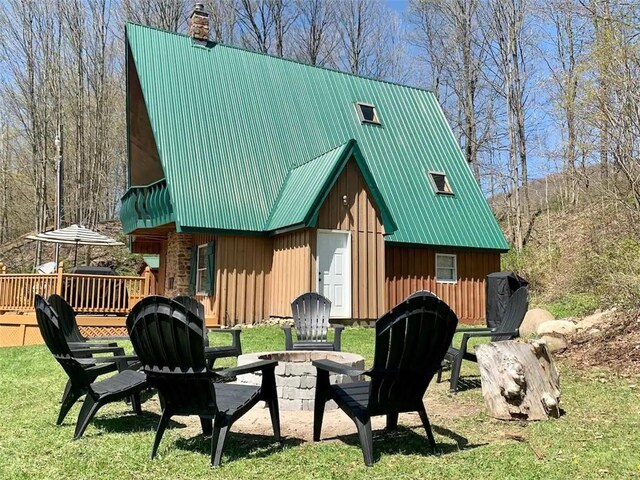 7136 Maples Rd, Mansfield, NY 14755 - exterior space with an outdoor fire pit, a chimney, a deck, metal roof, and board and batten siding