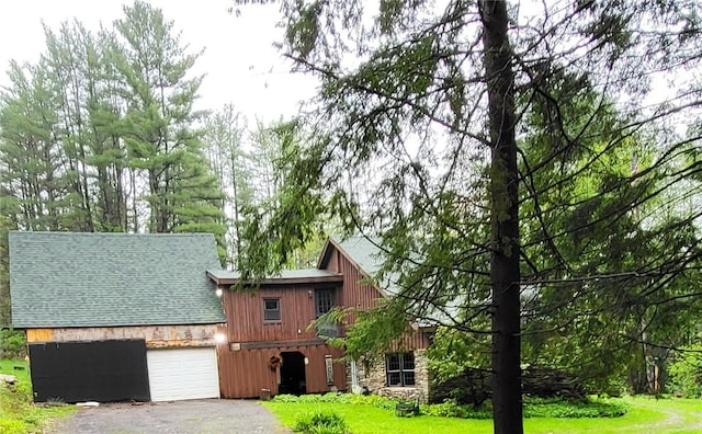607 Kilkenny Rd, Unadilla, NY 13849 - view of home's exterior with roof with shingles, driveway, stone siding, an attached garage, and a yard