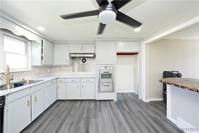 kitchen featuring a sink, oven, a warming drawer, and light wood finished floors