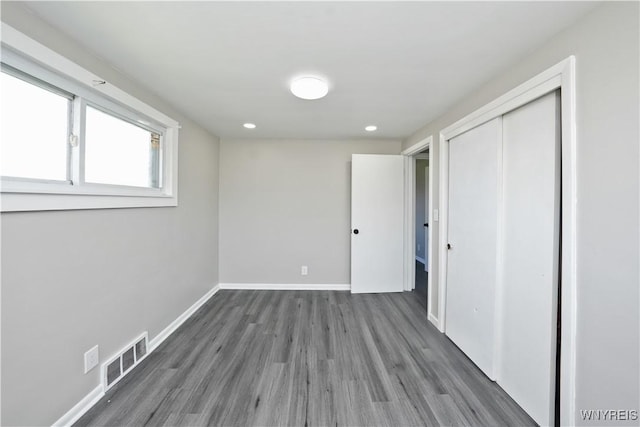 unfurnished bedroom with a closet, recessed lighting, baseboards, visible vents, and wood finished floors