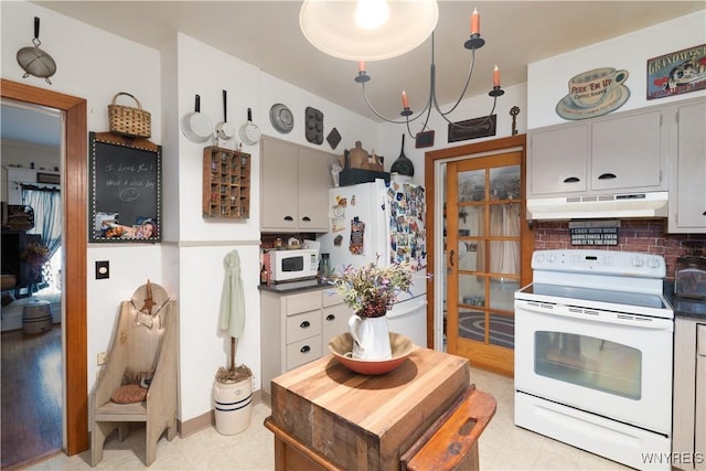 kitchen featuring white appliances, under cabinet range hood, backsplash, dark countertops, and light floors