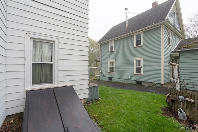 view of side of home featuring a lawn and a chimney