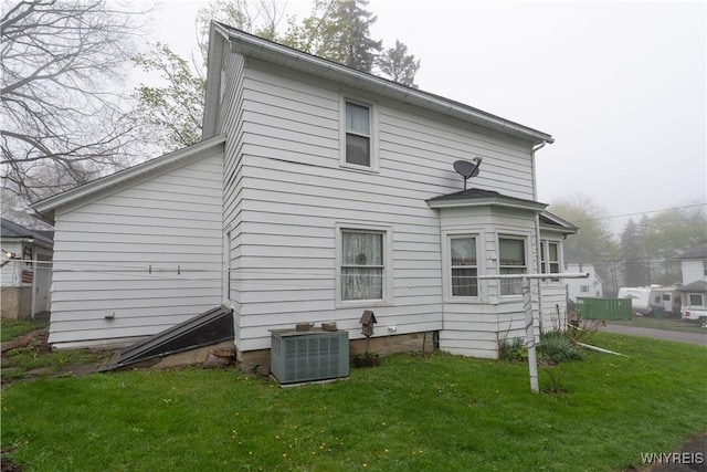 rear view of property featuring central AC unit and a yard