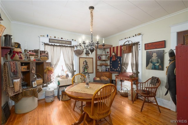 dining area with a chandelier, wood finished floors, and ornamental molding