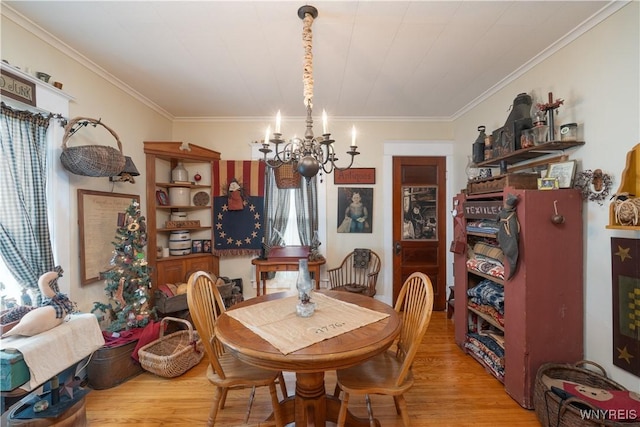 dining room with a chandelier, light wood finished floors, and crown molding