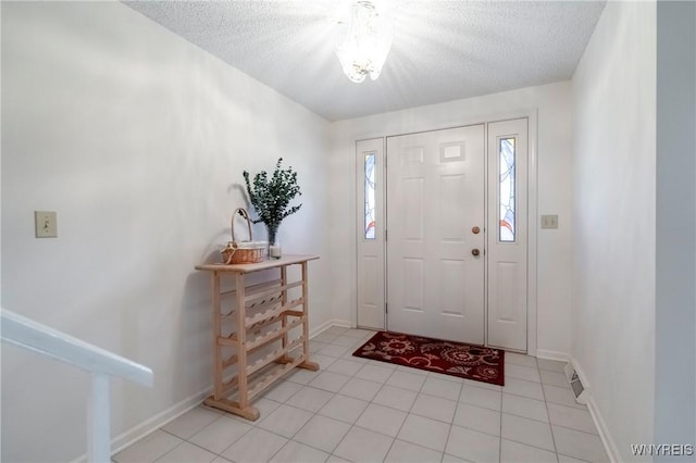 entryway with a textured ceiling, light tile patterned floors, baseboards, and a chandelier