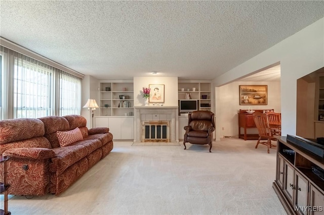living room featuring light colored carpet, a fireplace with flush hearth, a textured ceiling, and built in features