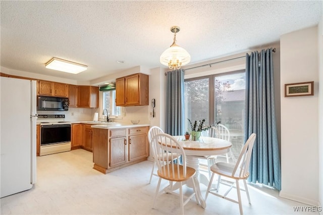 kitchen with white appliances, a textured ceiling, light countertops, a peninsula, and pendant lighting