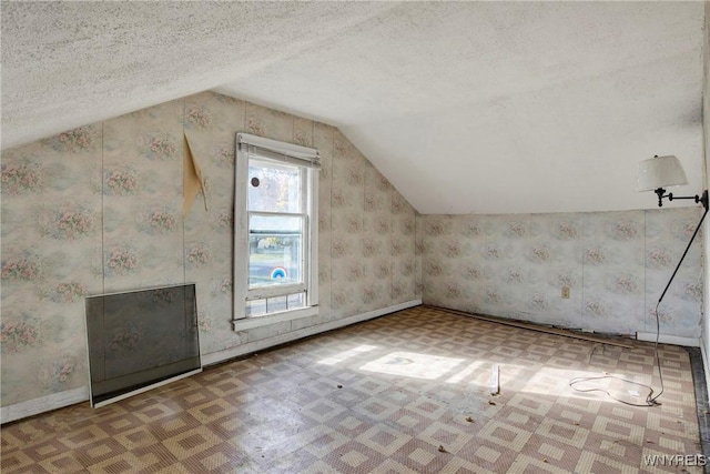 bonus room featuring vaulted ceiling, a textured ceiling, tile patterned floors, and baseboards