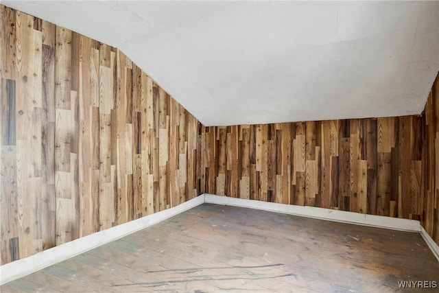 additional living space featuring vaulted ceiling, hardwood / wood-style floors, and wooden walls