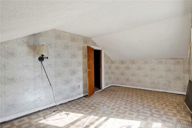 bonus room with vaulted ceiling, tile patterned floors, wallpapered walls, and baseboards
