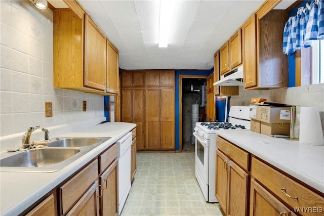 kitchen with white appliances, under cabinet range hood, a sink, and light countertops
