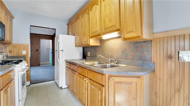 kitchen with light floors, white appliances, a sink, wood walls, and backsplash