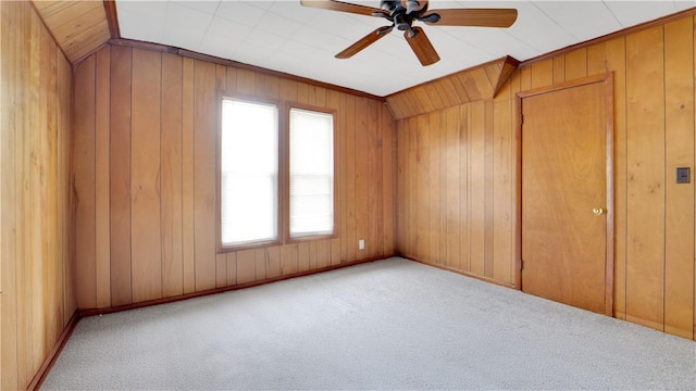 unfurnished room featuring wood walls, carpet flooring, and a ceiling fan