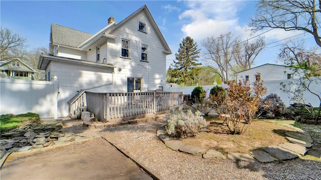 back of house featuring a chimney, a deck, and a fenced backyard