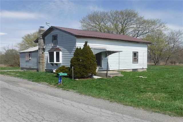 9867 Transit Rd, Pavilion, NY 14054 - exterior space with a chimney, metal roof, and a lawn