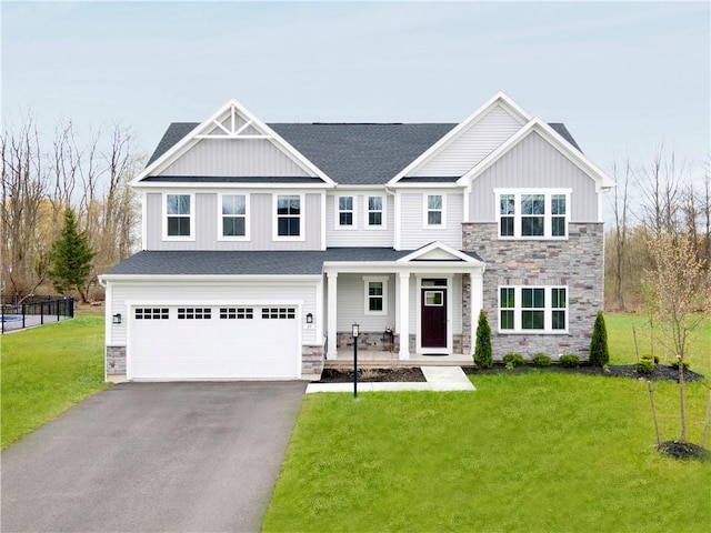 craftsman house with driveway, a front yard, a garage, stone siding, and a porch