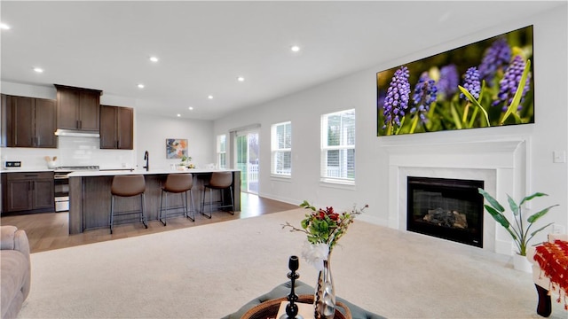 living room with light colored carpet, a glass covered fireplace, and recessed lighting