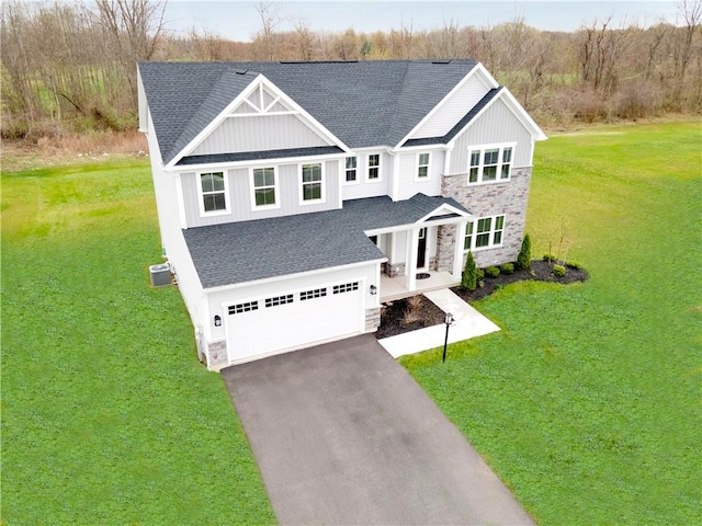 traditional home with stone siding, a shingled roof, an attached garage, and aphalt driveway