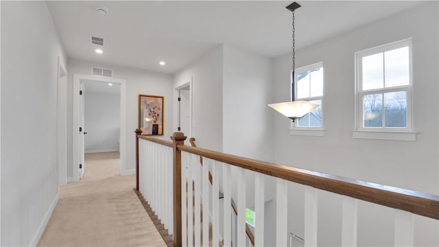 hallway featuring light colored carpet, visible vents, an upstairs landing, and baseboards