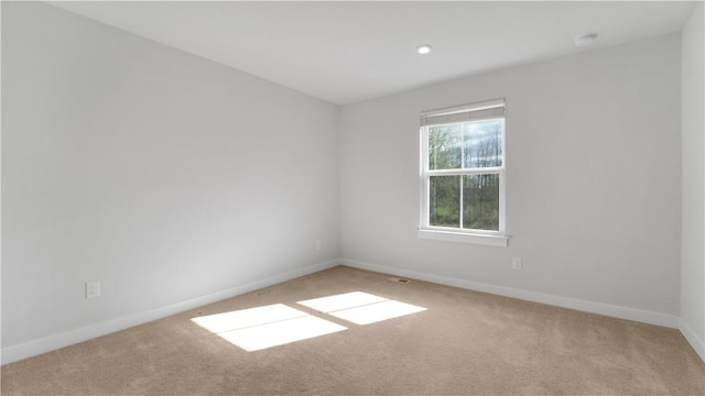 unfurnished room with light colored carpet and baseboards