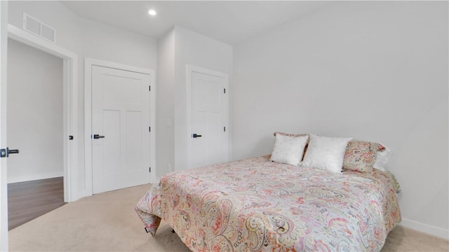 bedroom with light colored carpet, visible vents, baseboards, and recessed lighting