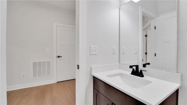 bathroom featuring vanity, baseboards, visible vents, and wood finished floors
