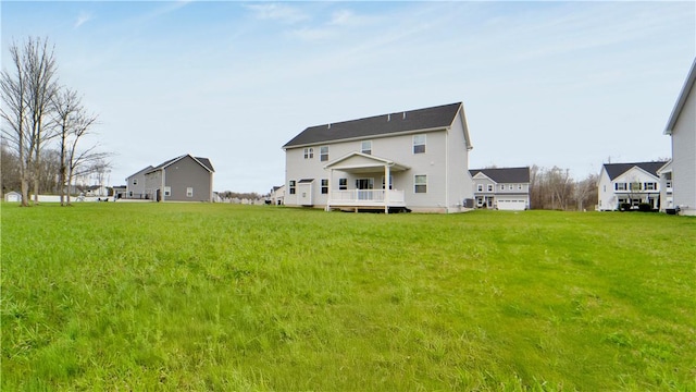 rear view of house featuring a wooden deck and a lawn