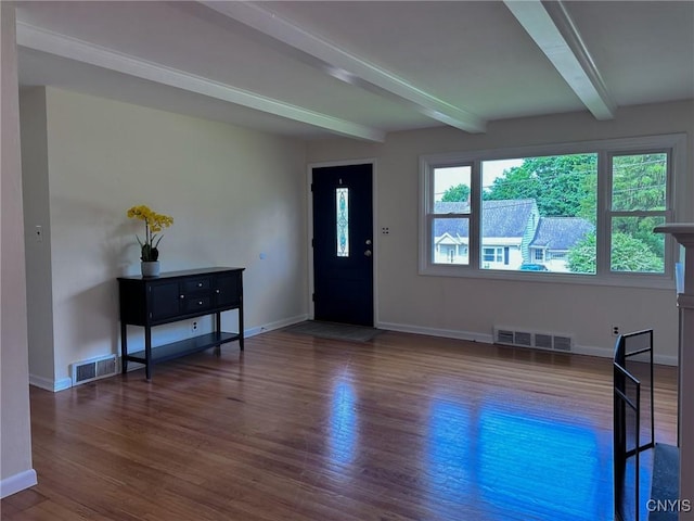 foyer entrance featuring baseboards, beamed ceiling, visible vents, and wood finished floors