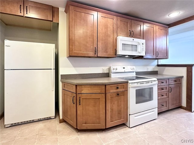 kitchen featuring recessed lighting, brown cabinetry, and white appliances