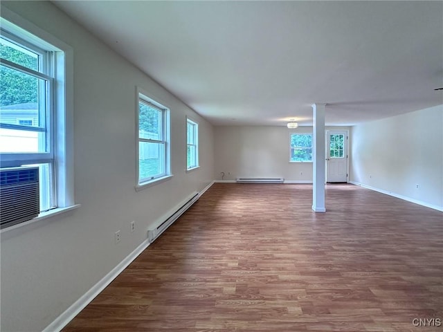 basement with baseboards, cooling unit, baseboard heating, and wood finished floors