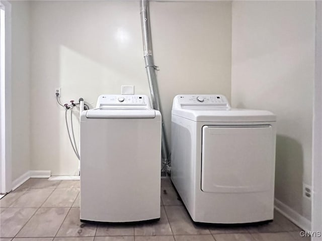 washroom featuring washer and clothes dryer, baseboards, and light tile patterned floors
