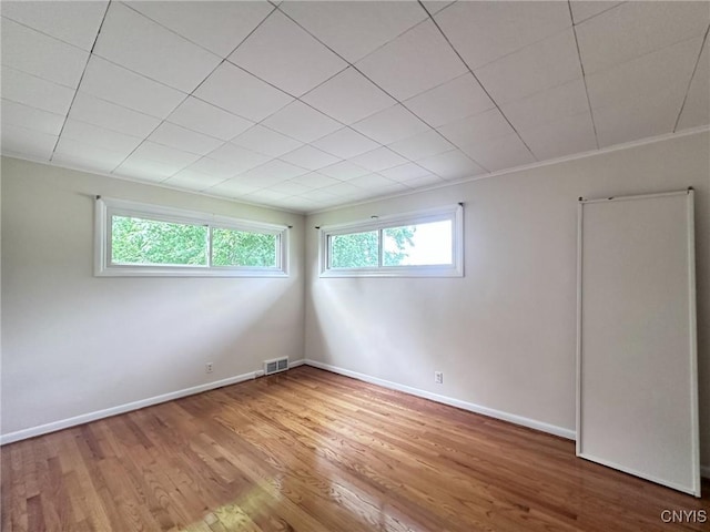 unfurnished room featuring visible vents, wood finished floors, and baseboards