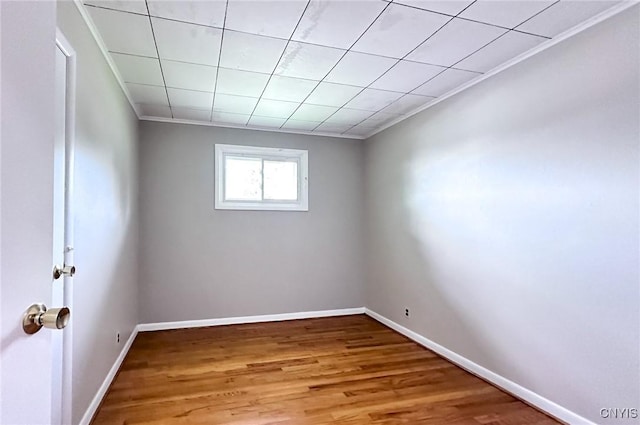 empty room with baseboards, crown molding, and wood finished floors