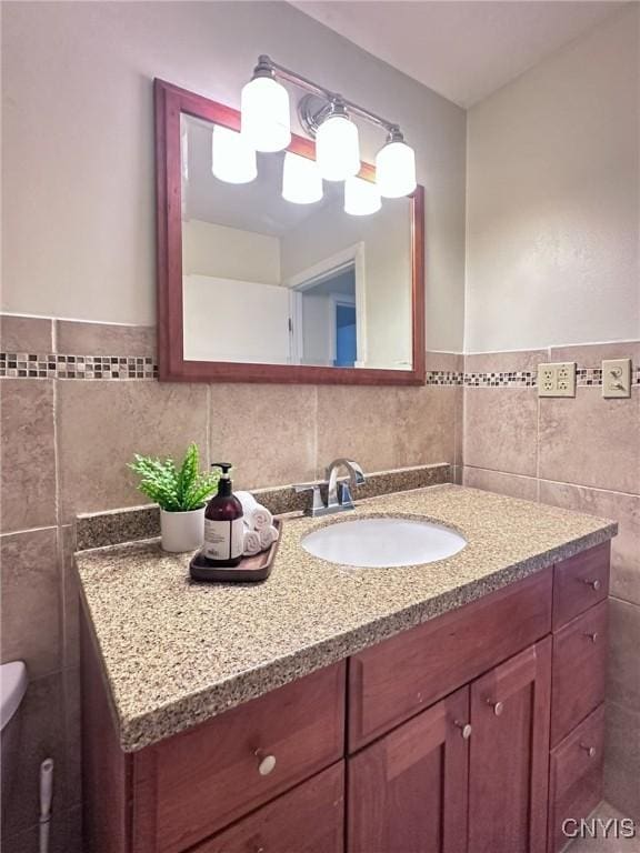 half bath with tile walls and vanity