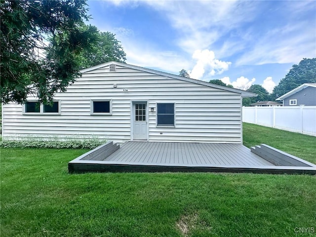 rear view of property featuring a yard, fence, and a deck