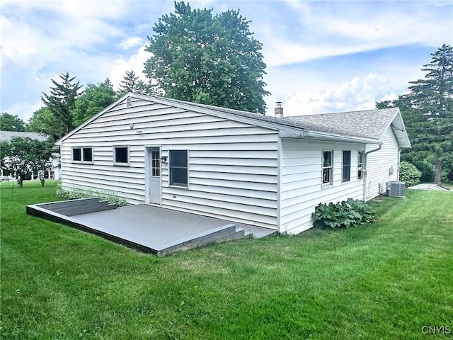back of property with a lawn, central air condition unit, and roof with shingles