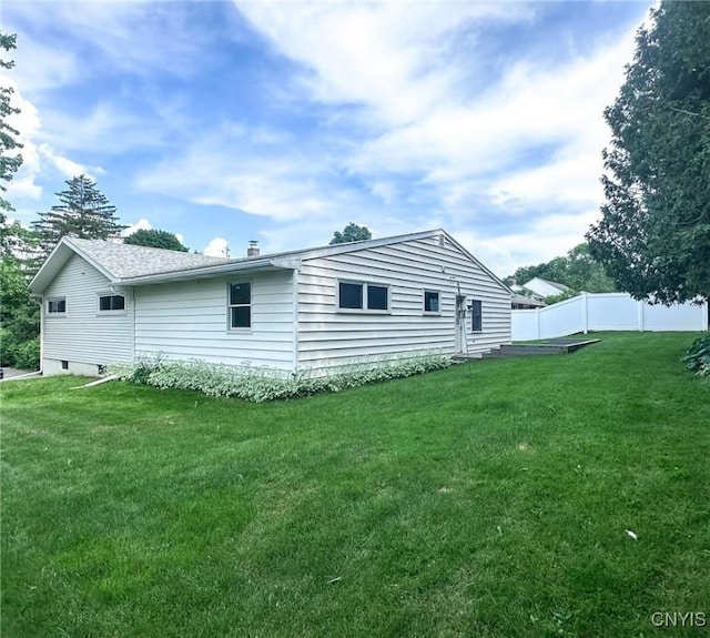 rear view of house with fence and a lawn