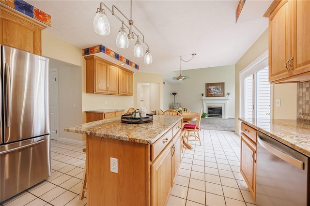 kitchen with a center island, a glass covered fireplace, light tile patterned flooring, open floor plan, and stainless steel appliances